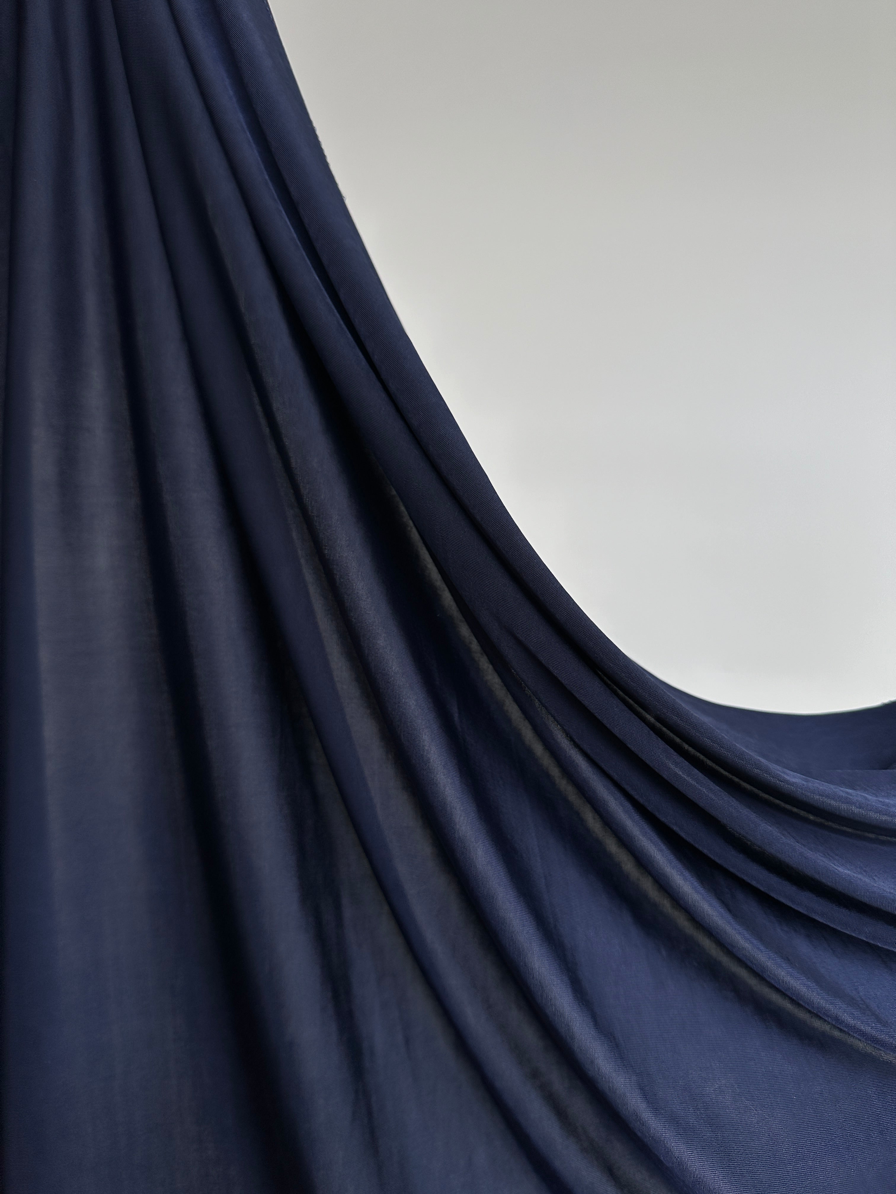 Texture satinée du hijab jersey liquide bleu nuit profond.