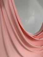 Détail de la couleur rose pêche poudré sur jersey liquide fluide.