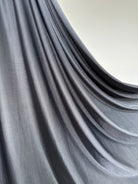Détail du jersey liquide gris foncé, aspect lisse et légèrement satiné.