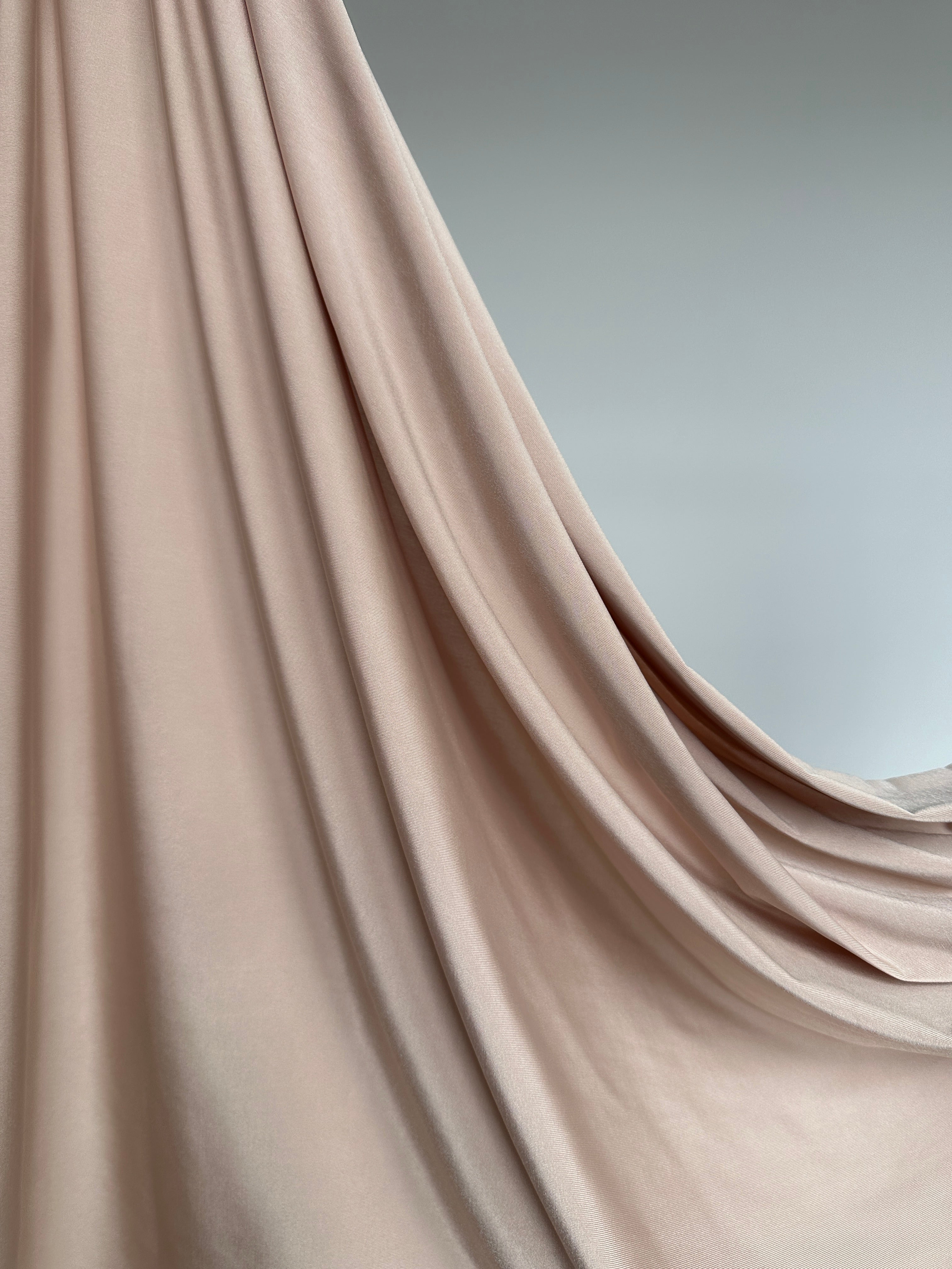 Détail du tissu jersey liquide beige , texture fluide et extensible.